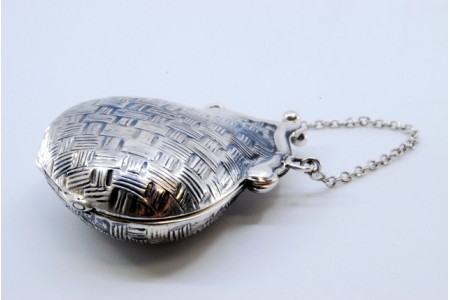 Caixa de comprimidos em prata guilhochada em forma de bolsa com corrente e fecho basculante.